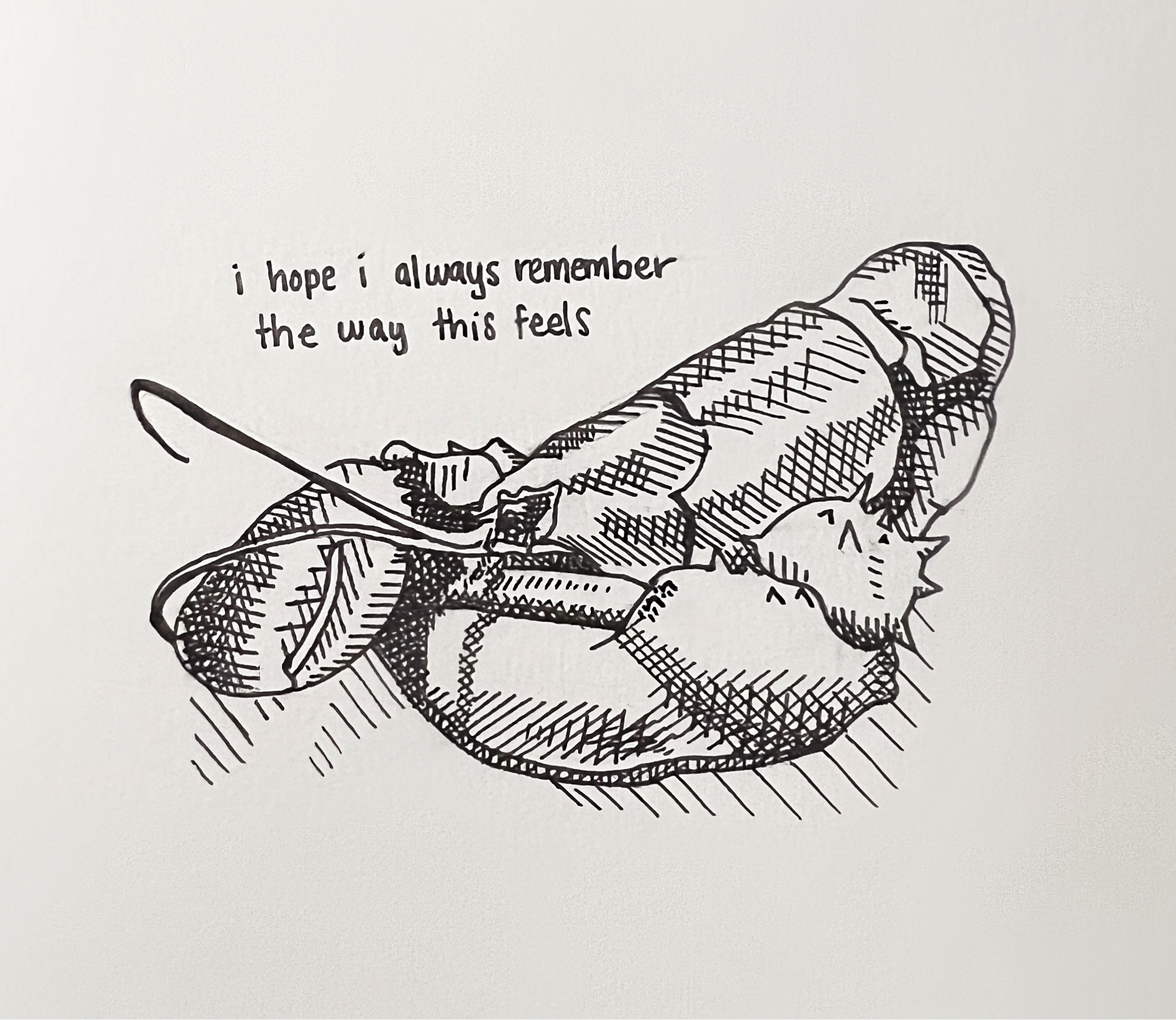 A black ink drawing of a figure curled under a blanket with a cat, beneath the handwritten words “i hope i always remember the way this feels”